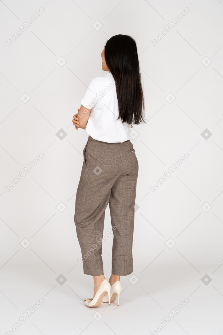 Vista posterior de tres cuartos de una mujer joven en calzones cruzando las manos