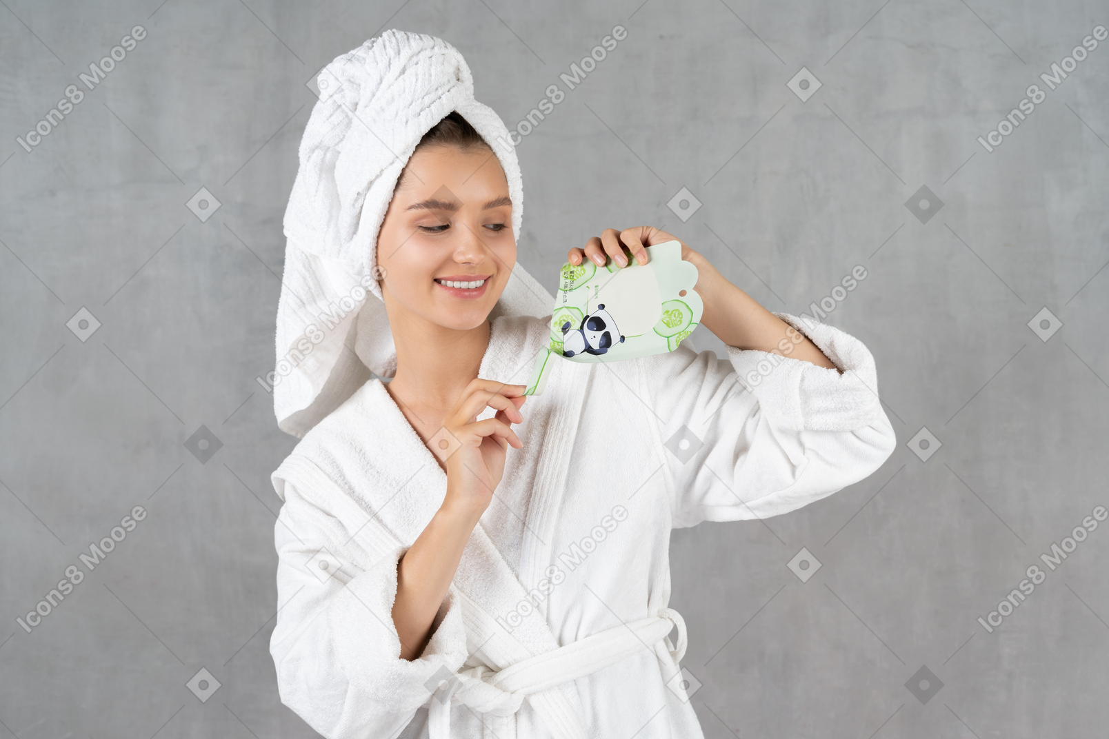 Smiling woman in bathrobe opening a sheet mask pack