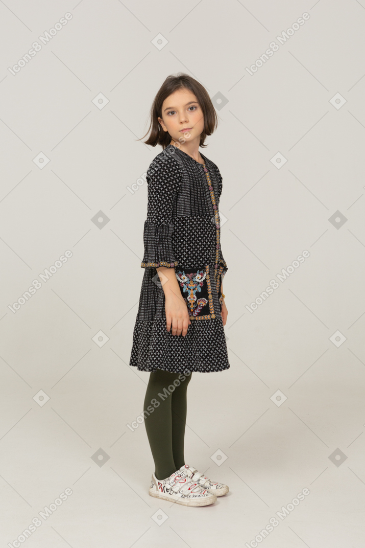 Vista de tres cuartos de una niña vestida mirando a la cámara