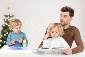 A man reading a book to two children