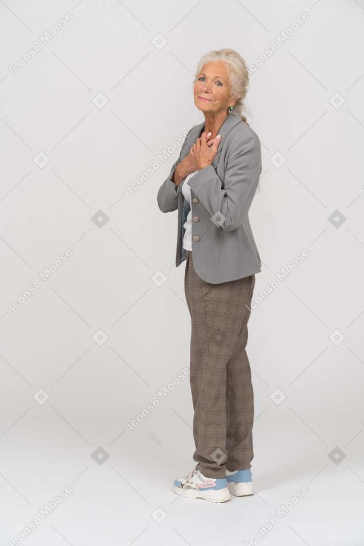 Vista lateral de una anciana en traje mirando a la cámara