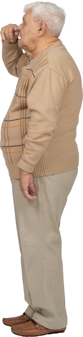Vista laterale di un vecchio in abiti casual toccando il naso