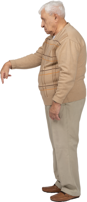 一位身穿休闲服的老人用手指向下指的侧视图