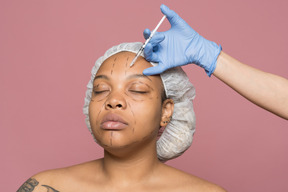 Afroamerikanerfrau, die botox-injektion in ihre stirn bekommt