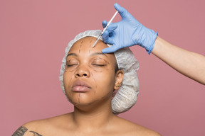 Mujer afroamericana recibiendo inyección de botox en la frente