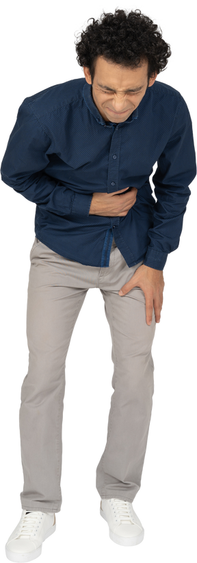 Front view of a man in casual clothes suffering from stomachache