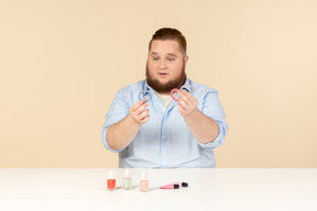 Big man looking attentively at hair bands he's holding