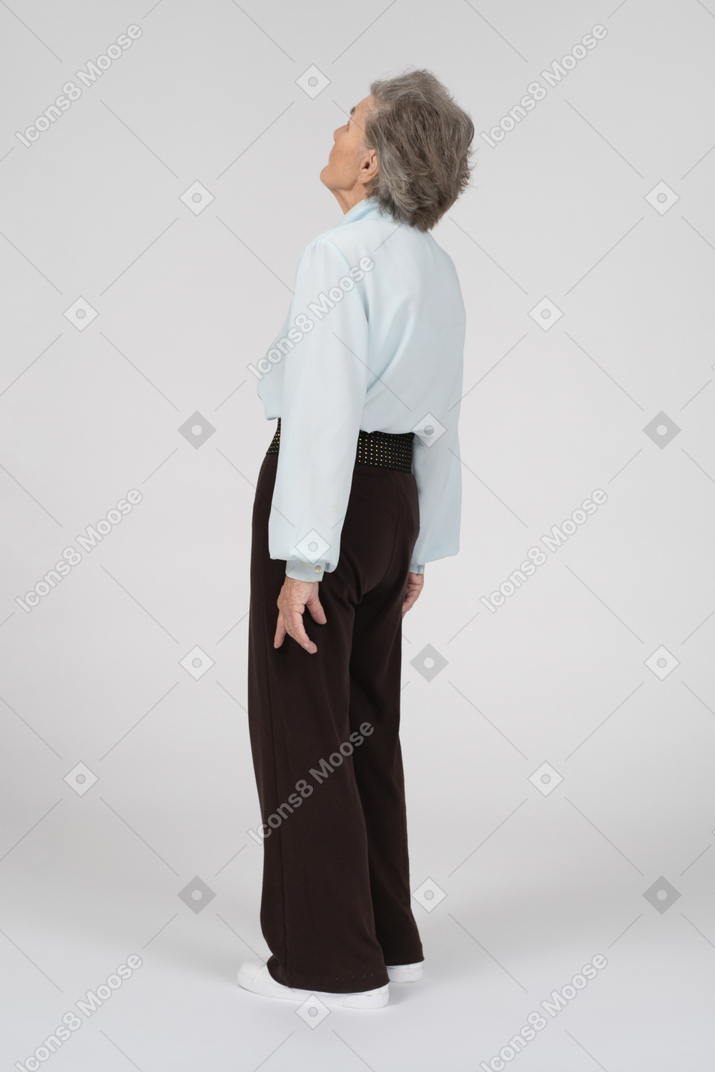 Three-quarter back view of an old woman looking up