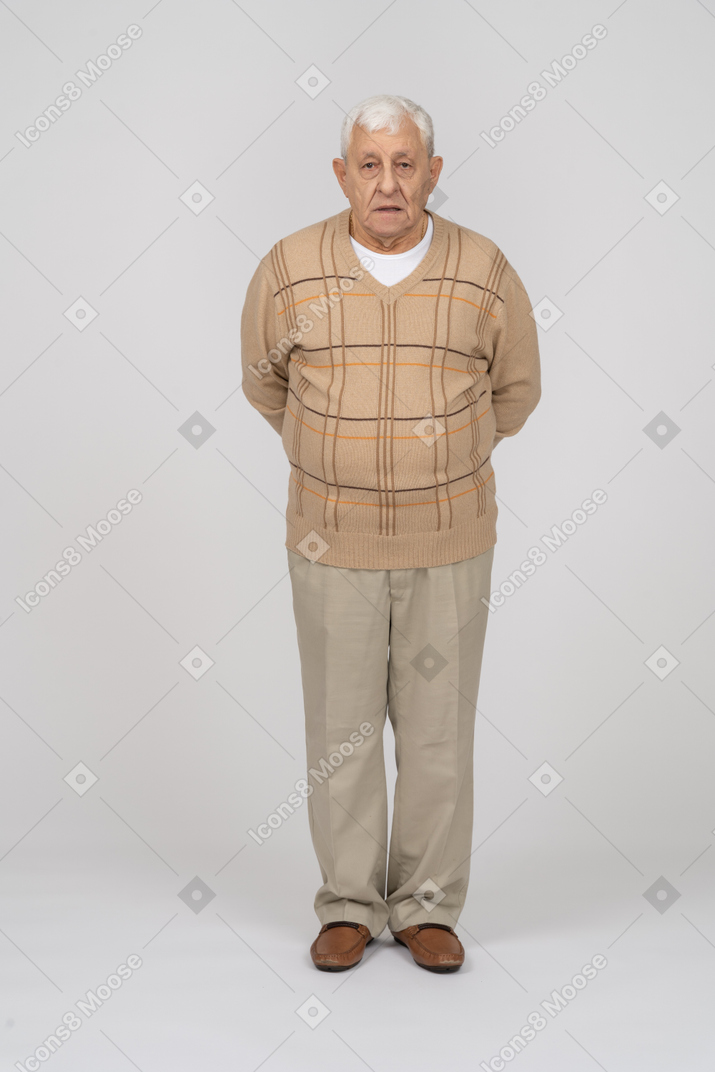 一位身穿休闲服、双手背在身后站立的老人的正面图