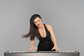 Una mujer joven feliz disfrutando tocando el piano