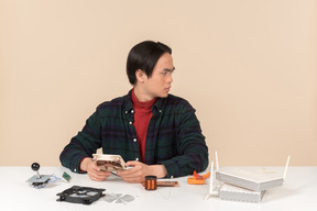 Ein asiatischer geek-typ in einem dunklen karierten hemd, der mit computerdetails arbeitet