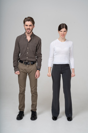 Front view of a furious couple in office clothing clenching fists