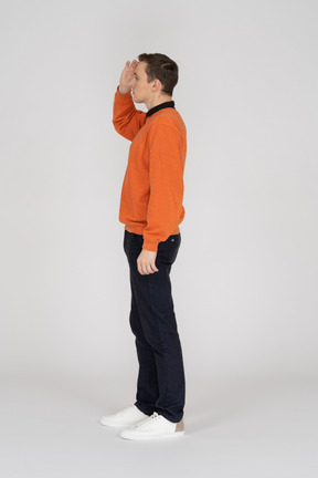 Молодой человек в оранжевой кофте стоит