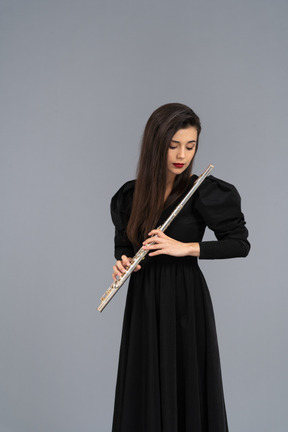 Front view of a serious young lady in black dress holding flute