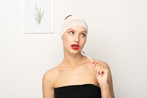 Portrait of a young woman sticking syringe into her mouth