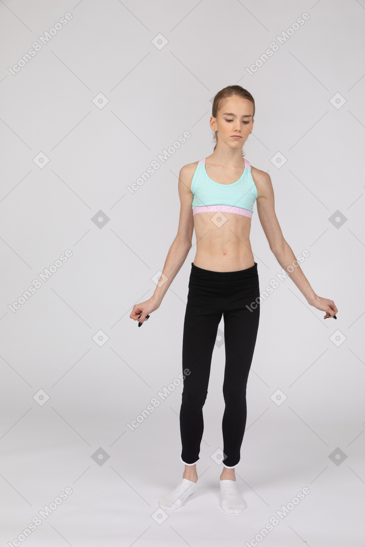 一个十几岁的女孩，在伸出她的手臂时跳舞的运动服的前视图