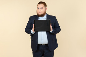 Joven oficinista con sobrepeso mostrando tableta digital