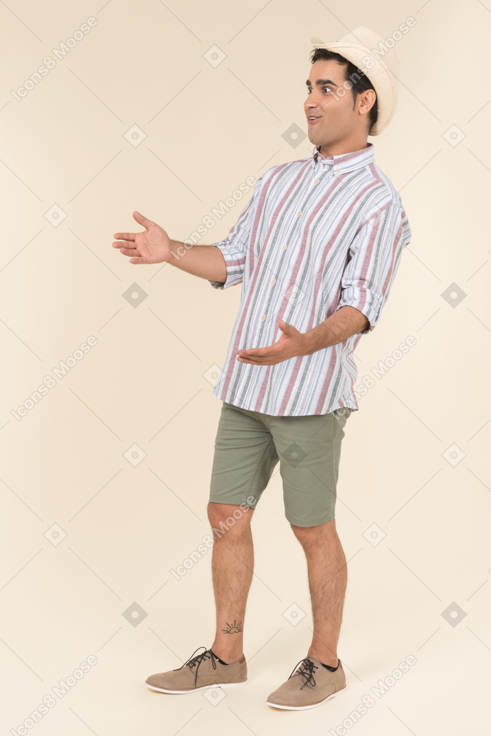 Excited young guy standing with hands on both sides