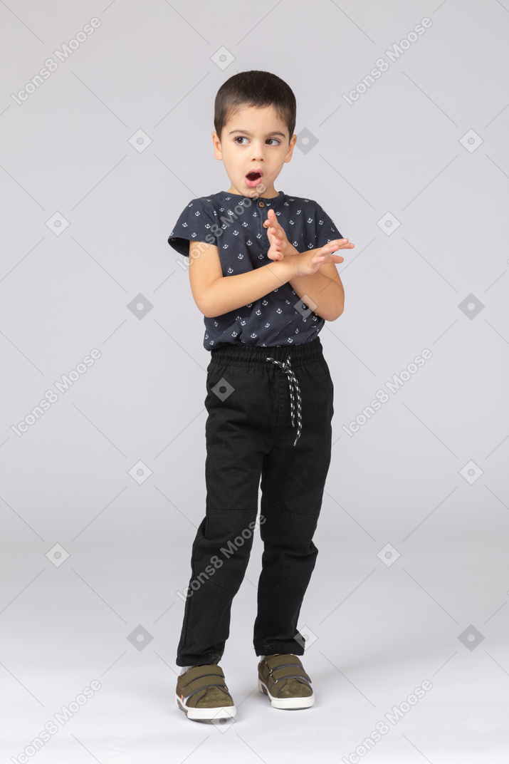 一个穿着休闲服的可爱男孩打哈欠并展示停止手势的前视图