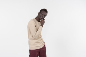 A young black man in a grey sweater standing alone on the white background