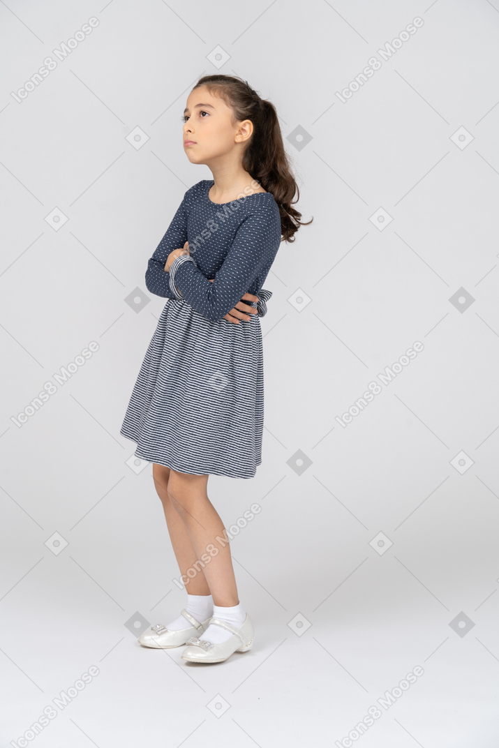 Three-quarter view of a girl with hands folded pouting absent-mindedly
