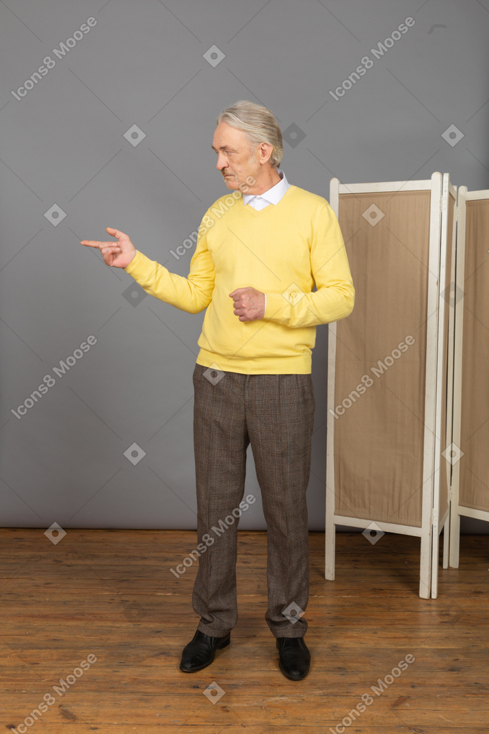 Vista frontal de un anciano interrogante levantando la mano mientras mira a un lado