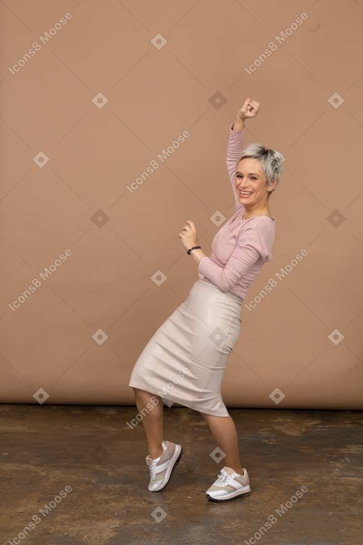 Vista lateral de uma mulher feliz em roupas casuais dançando