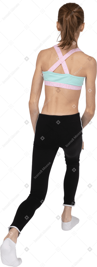 Vista traseira de três quartos de uma adolescente em uma roupa esportiva dando uma estocada