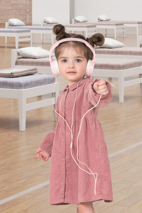 A little girl wearing headphones and a pink dress