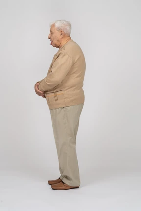 Side view of an old man in casual clothes showing tongue