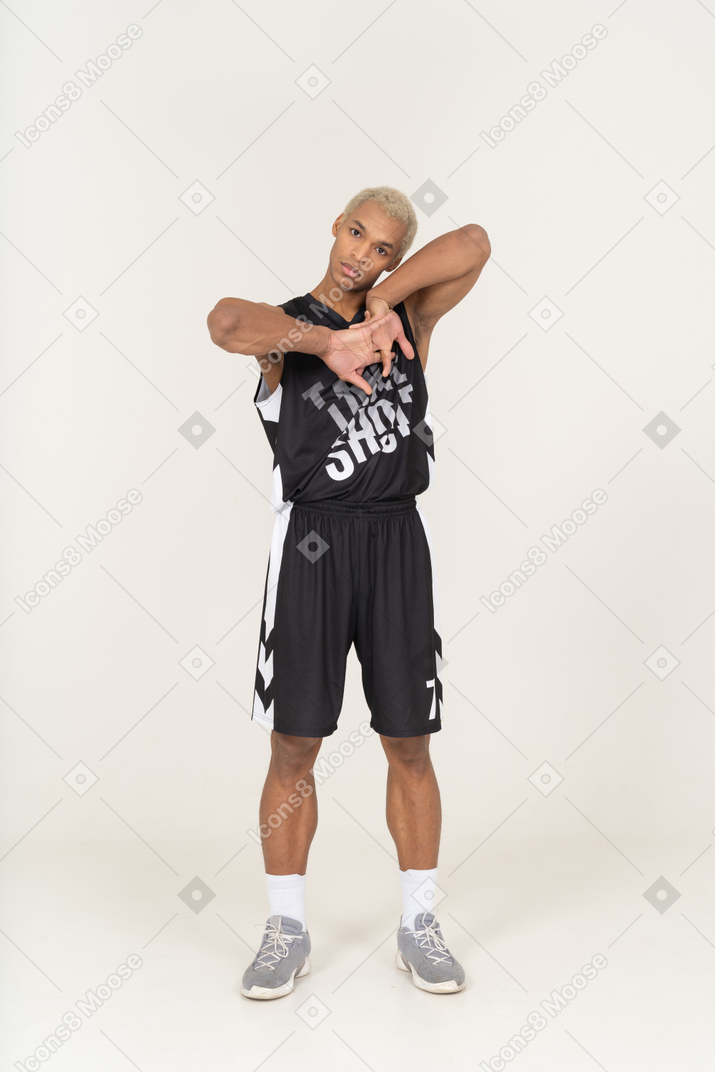 手を上げて頭を傾ける若い男性バスケットボール選手の正面図
