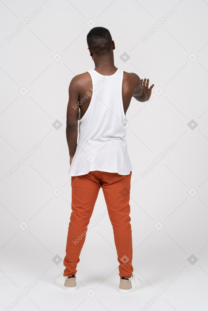 片方の腕を前方に伸ばして立っている若い黒人男性の背面図