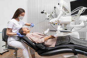 Longitud total de una dentista curando a su paciente acostada en un gabinete de hospital