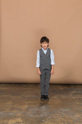 Front view of a boy in suit standing still and looking at camera