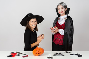 Boy in vampire costume showing pile of candies to mum