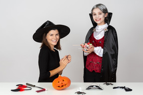 Ragazzo in costume da vampiro che mostra un mucchio di caramelle alla mamma