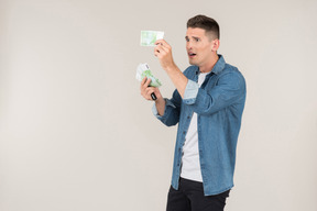 Young stand-up comic looking carefully at banknotes he's holding