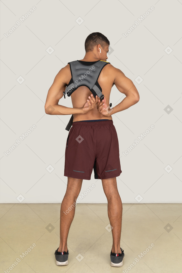 A back side view of the athletic guy wearing a life vest and looking right
