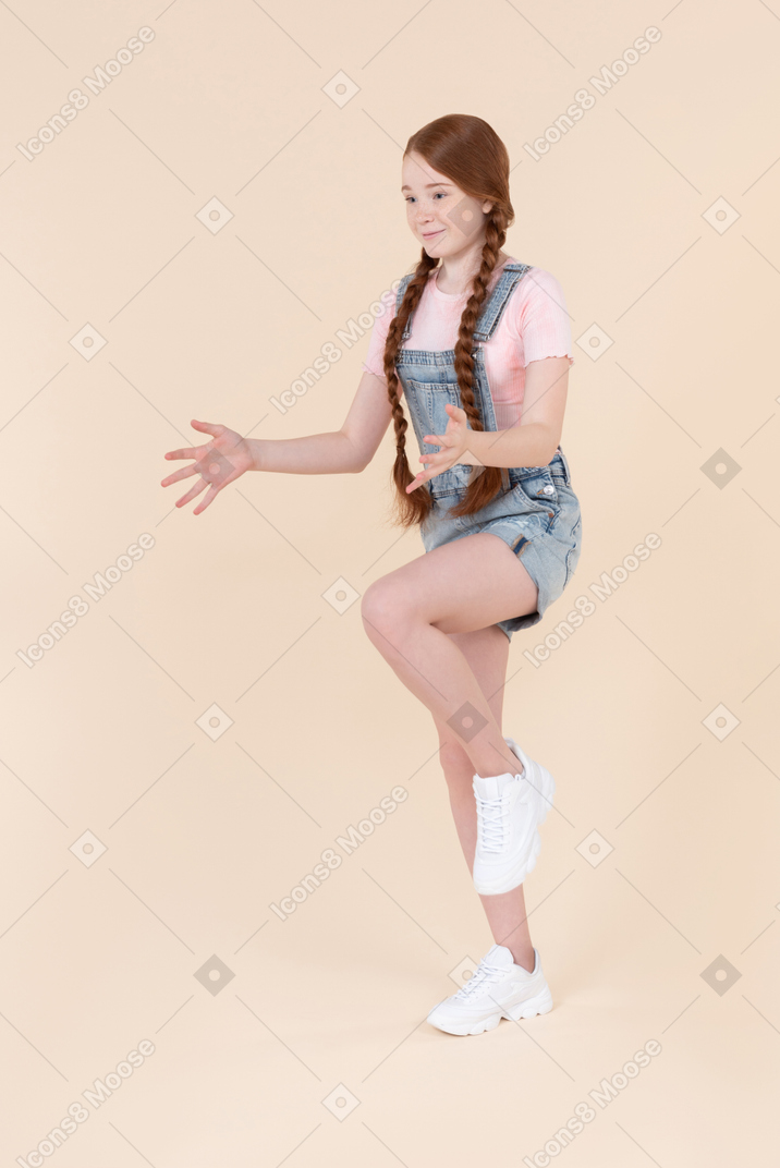 Teenage girl standing in kicking ball by knee position