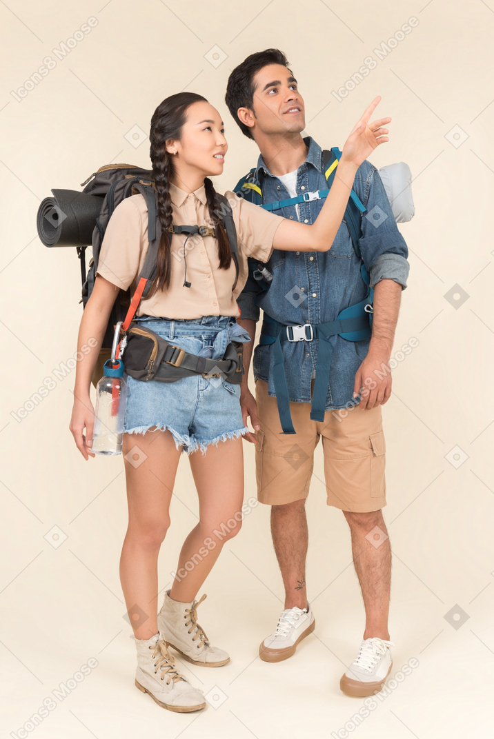 Young female traveller pointing at something to her boyfriend