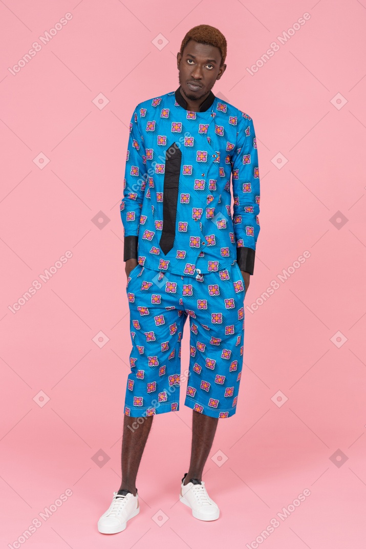 Homme noir en pyjama bleu debout sur fond rose