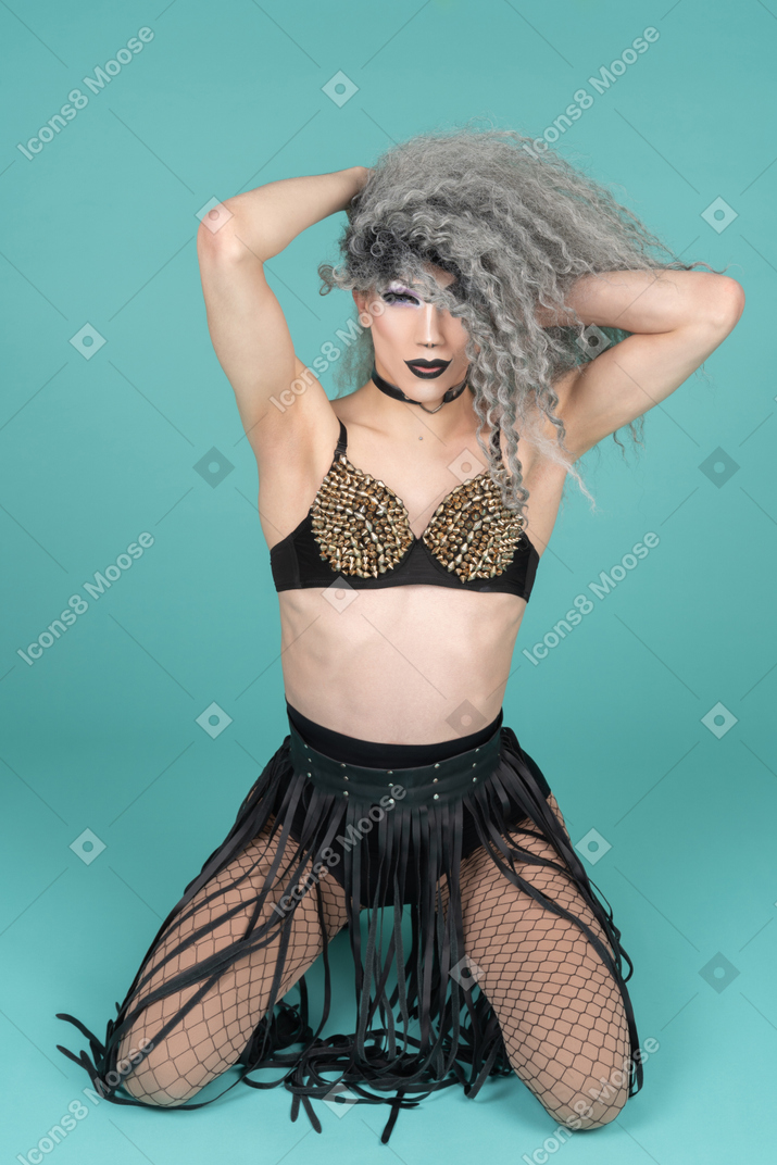 Drag queen standing on knees with hands behind their head