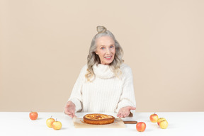 Elegante anciana que ofrece probar su tarta de manzana recién horneada