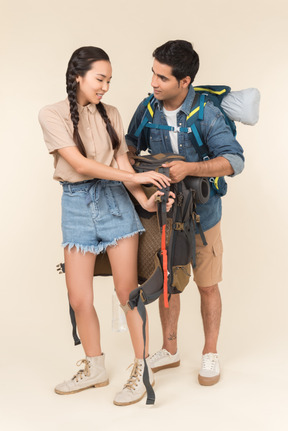 Junger mann hilft seiner asiatischen freundin rucksack ausziehen