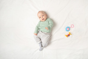 Baby girl lying on the back near children toys