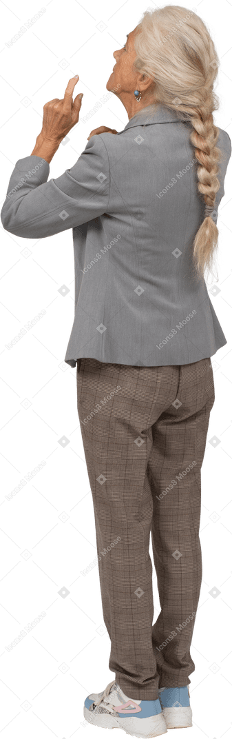Rear view of an old lady in suit pointing up with finger