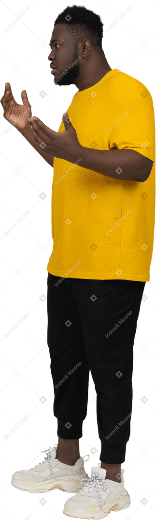 Vista di tre quarti di un giovane uomo dalla pelle scura che discute gesticolando in maglietta gialla