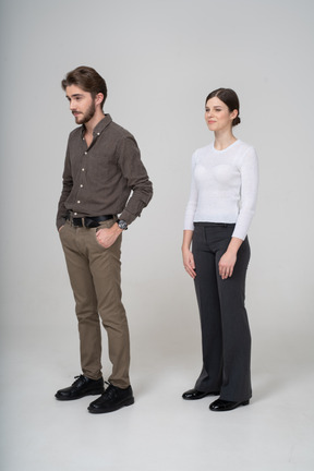 Vista di tre quarti di una giovane coppia sospettosa in abiti da ufficio