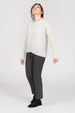 Young woman in sweater and pants looking up