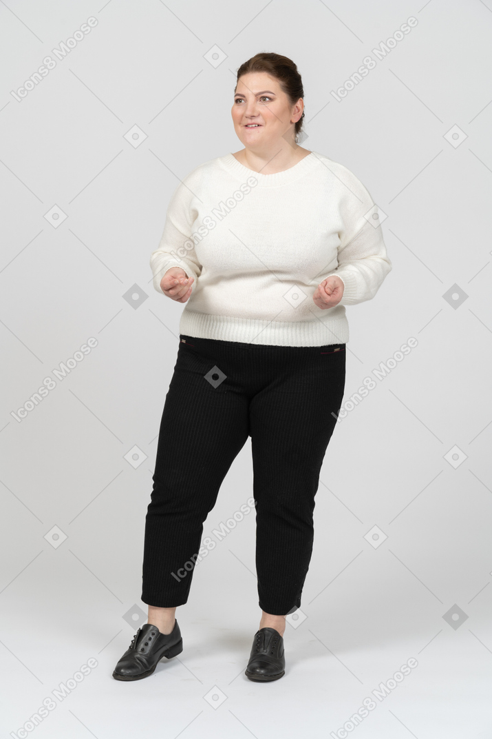 Felice donna grassoccia in maglione bianco che fa facce